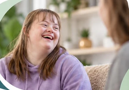 A young woman laughing while chatting with her support worker at home